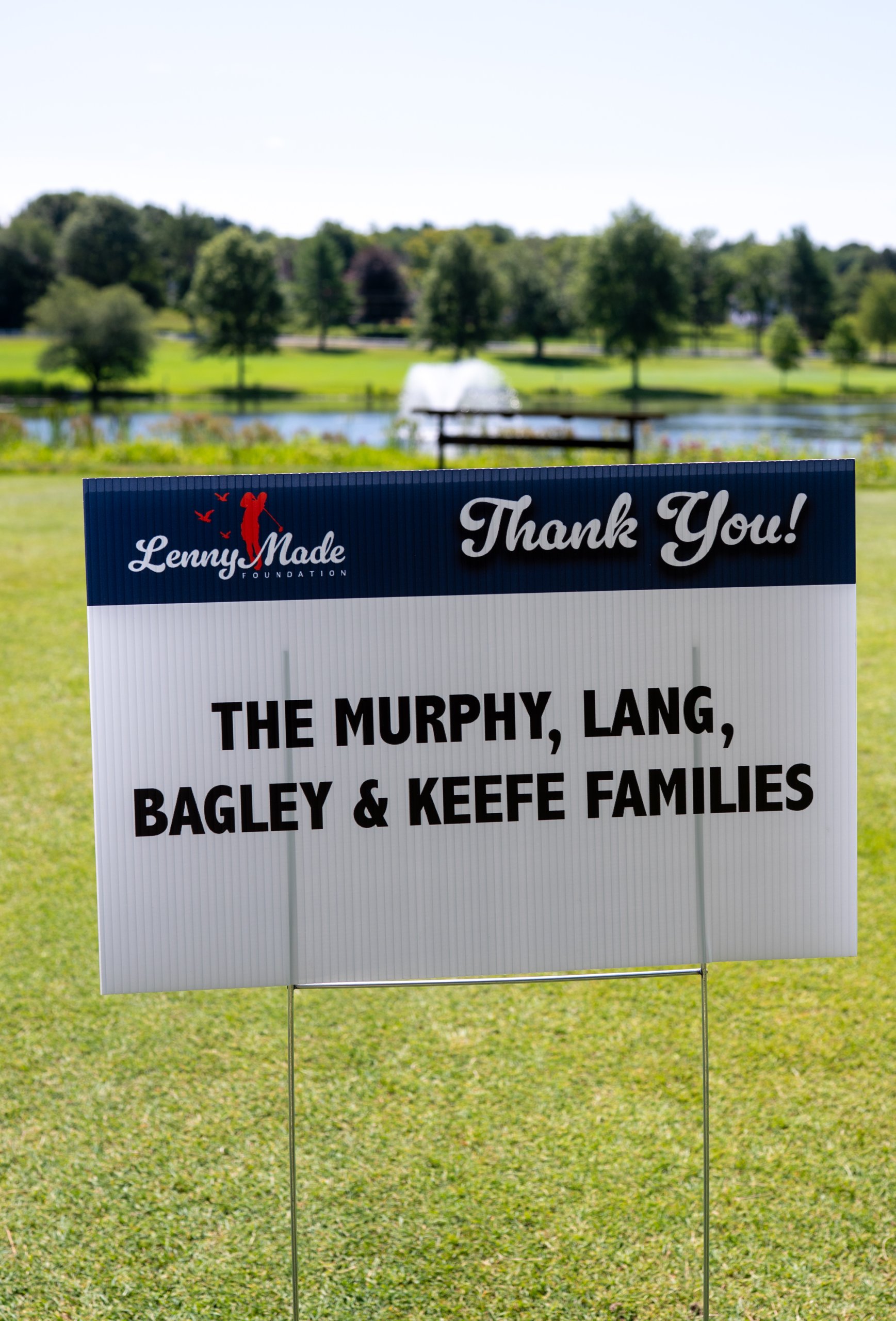 A LennyMade Foundation Thank You sponsor sign for the Murphy, Lang, Bagley and Keefe Families, a fountain pond behind.