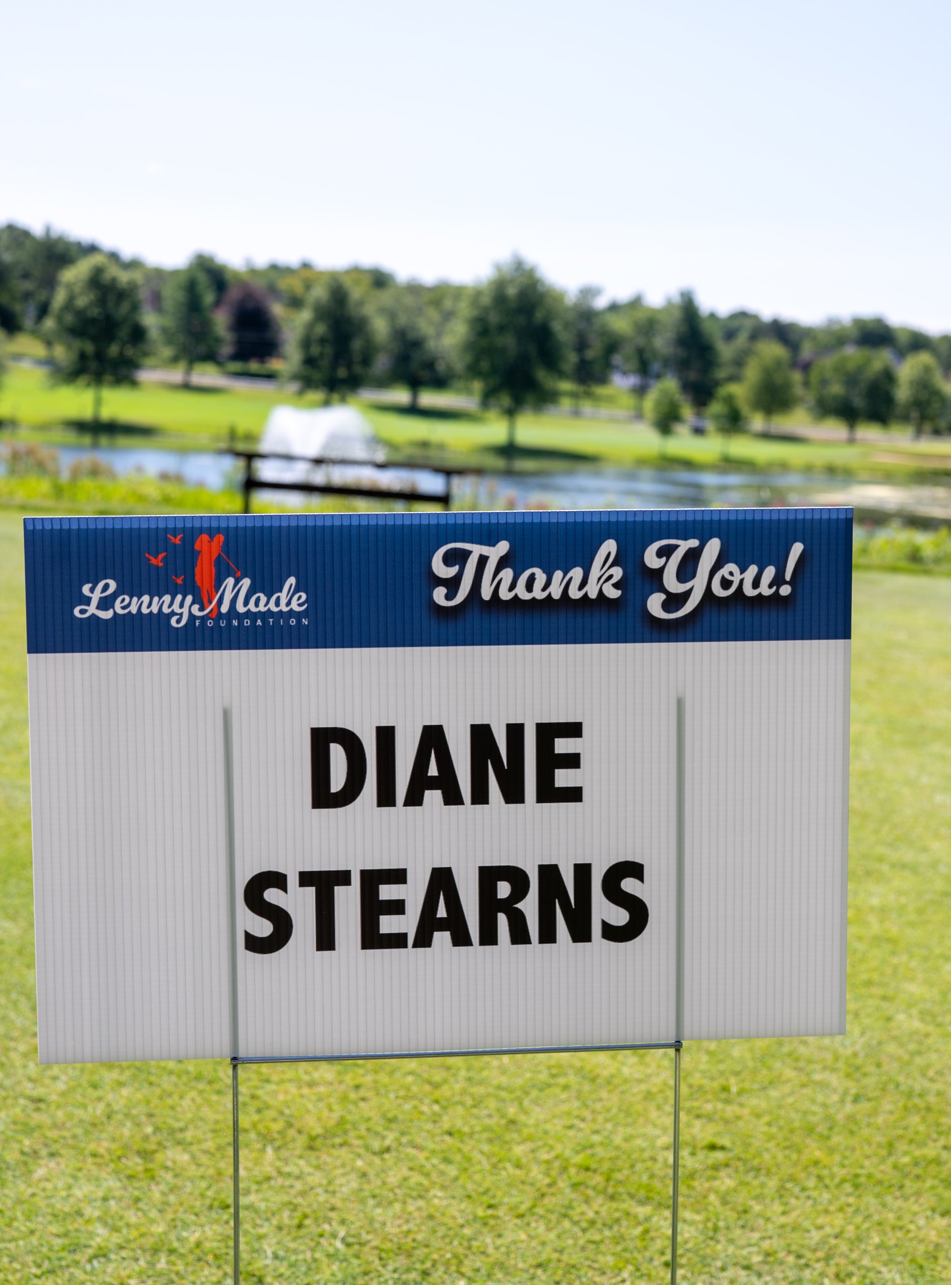 A LennyMade Foundation Thank You sponsor sign for Diane Stearns, with the fountain pond in the background.