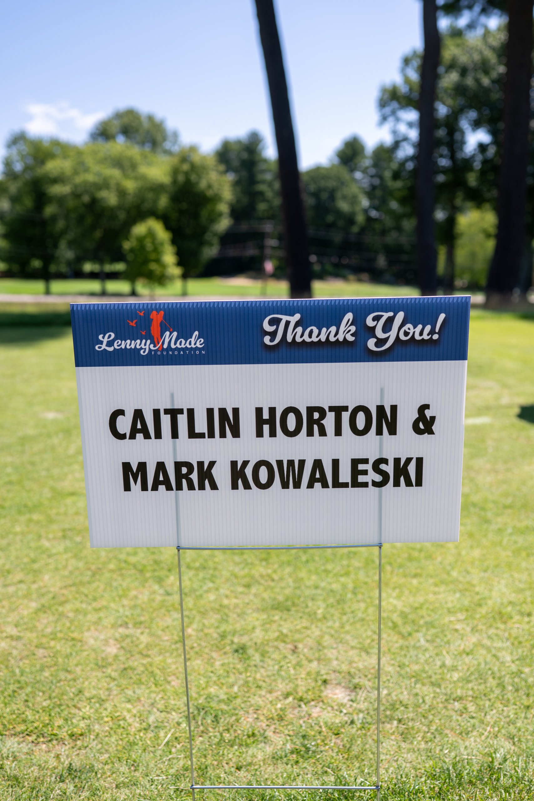A LennyMade Foundation Thank You sponsor sign for Caitlin Horton and Mark Kowaleski on the course.