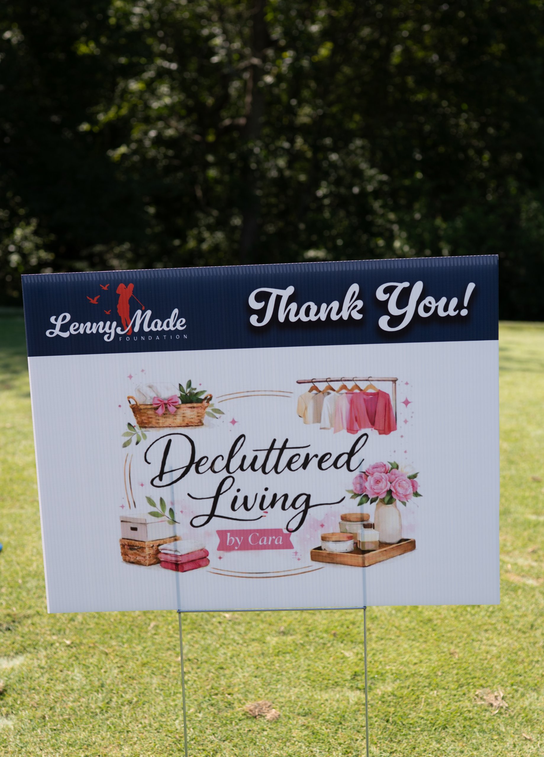 A LennyMade Foundation Thank You sponsor sign for Decluttered Living by Cara staked in the grass.