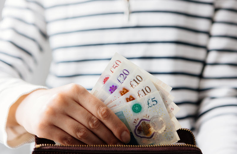 Hand holding UK pound notes representing supporting artist pay.