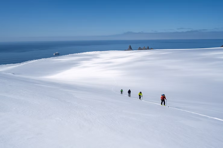 Four-Skiers-follow-path-in-Antarctica-near-ocean.jpg