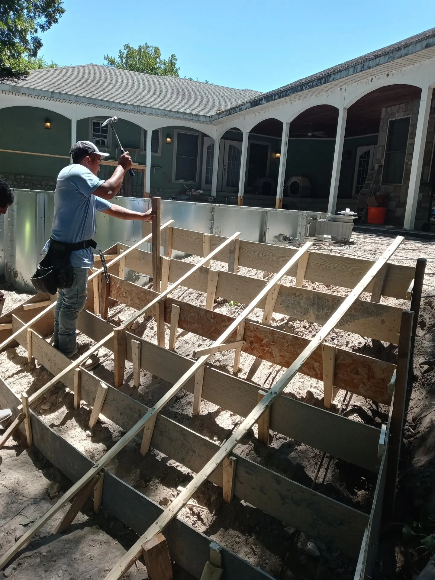 Installing concrete stairs next to semi-inground pool on a sloped backyard in Tulsa.