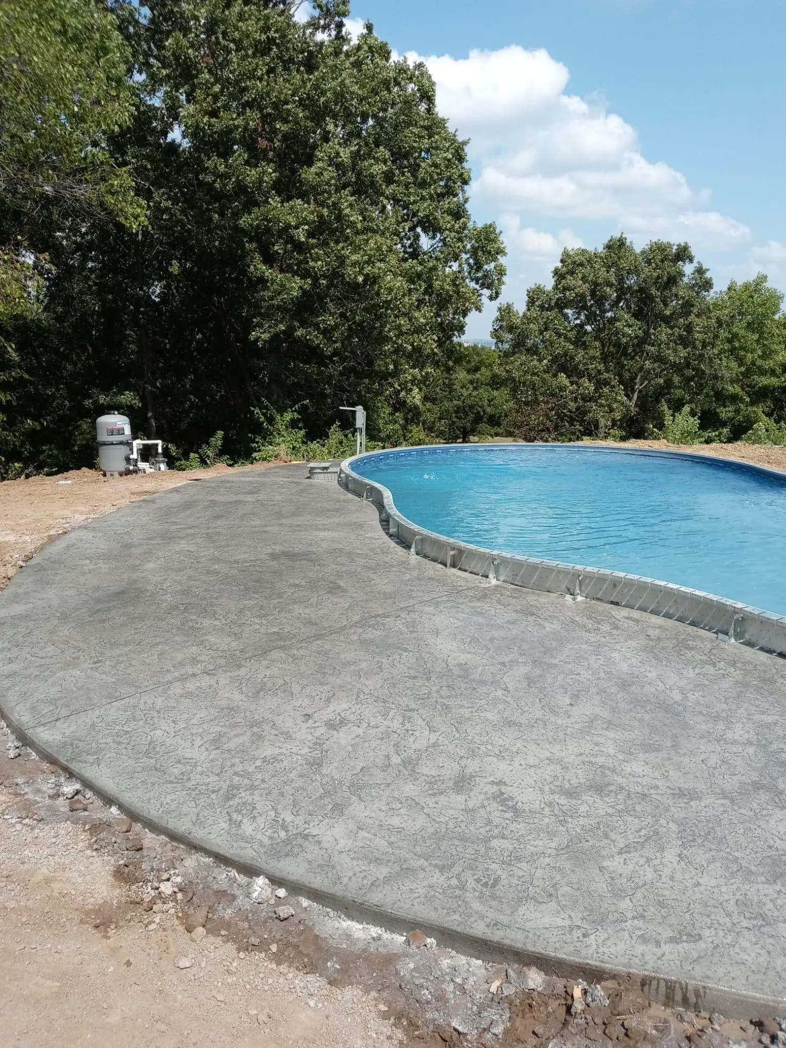 Semi inground swimming pool with concrete decking in Tulsa, OK.