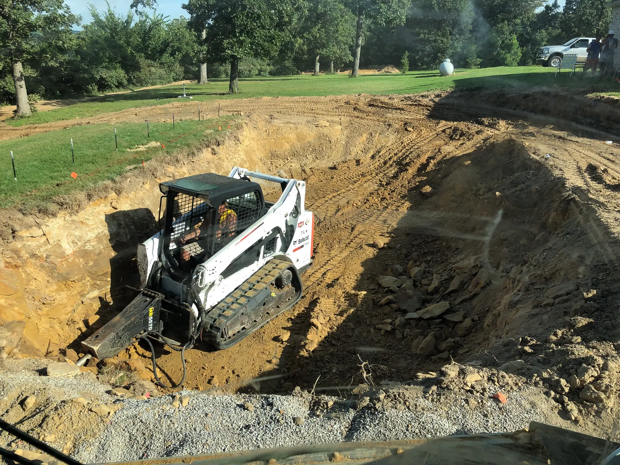 Digging through burried rock for fiberglass pool install.