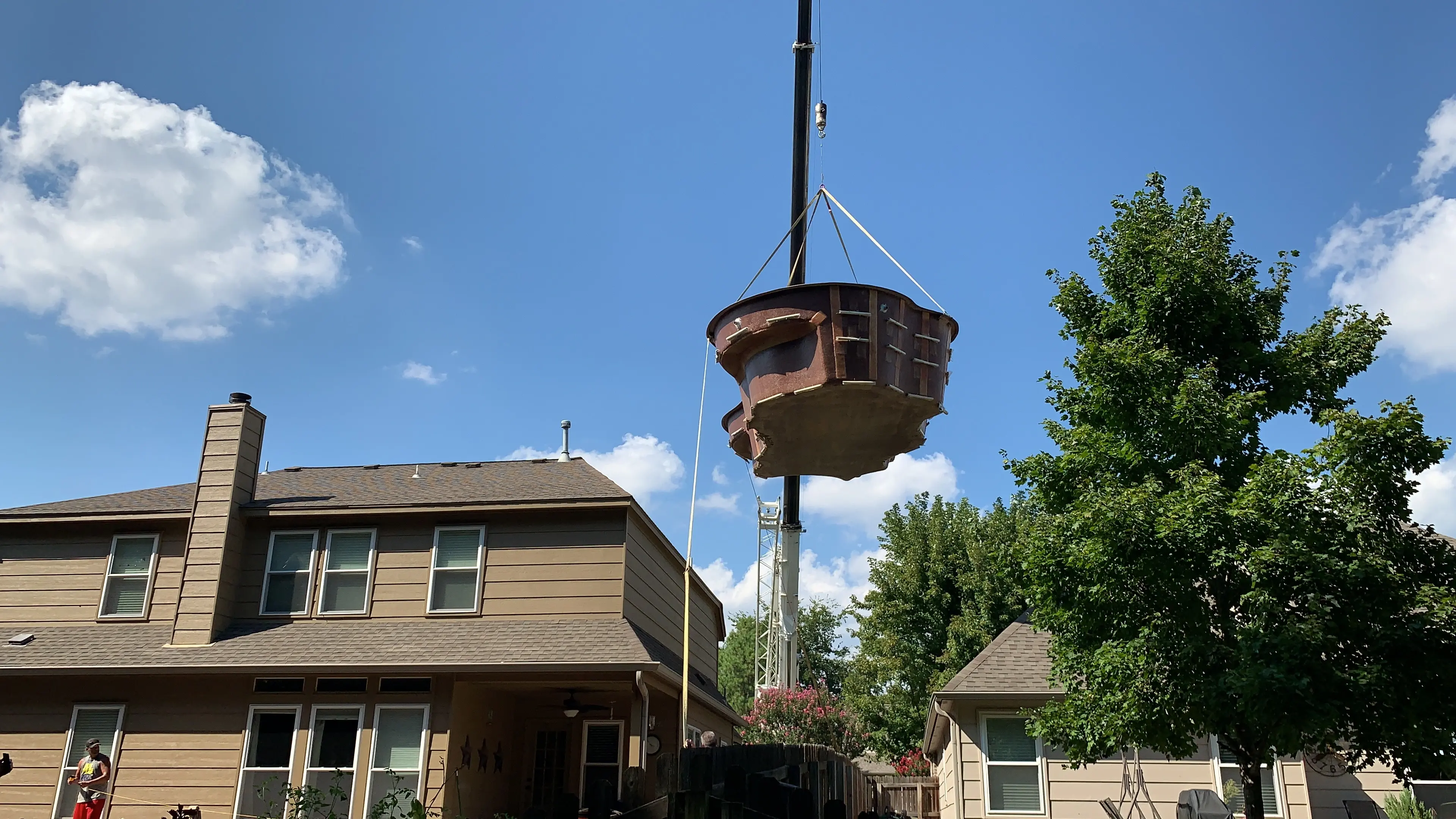 Crane lifting fiberglass pool over house in Tulsa, OK.