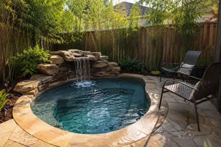 Compact in-ground plunge pool with rock wall and waterfall for a very small Tulsa yard.