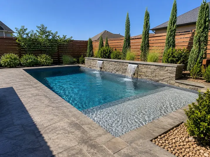 Rectangular in-ground pool with limestone wall and tanning ledge in a small Bixby backyard.