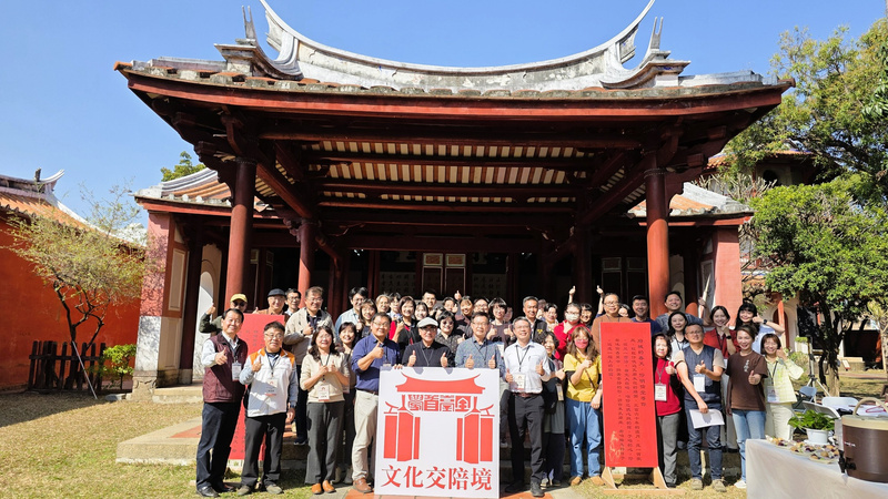 文化交流活動合照，眾多參與者於傳統古蹟建築前合影，展現文化保存與社區參與的成果